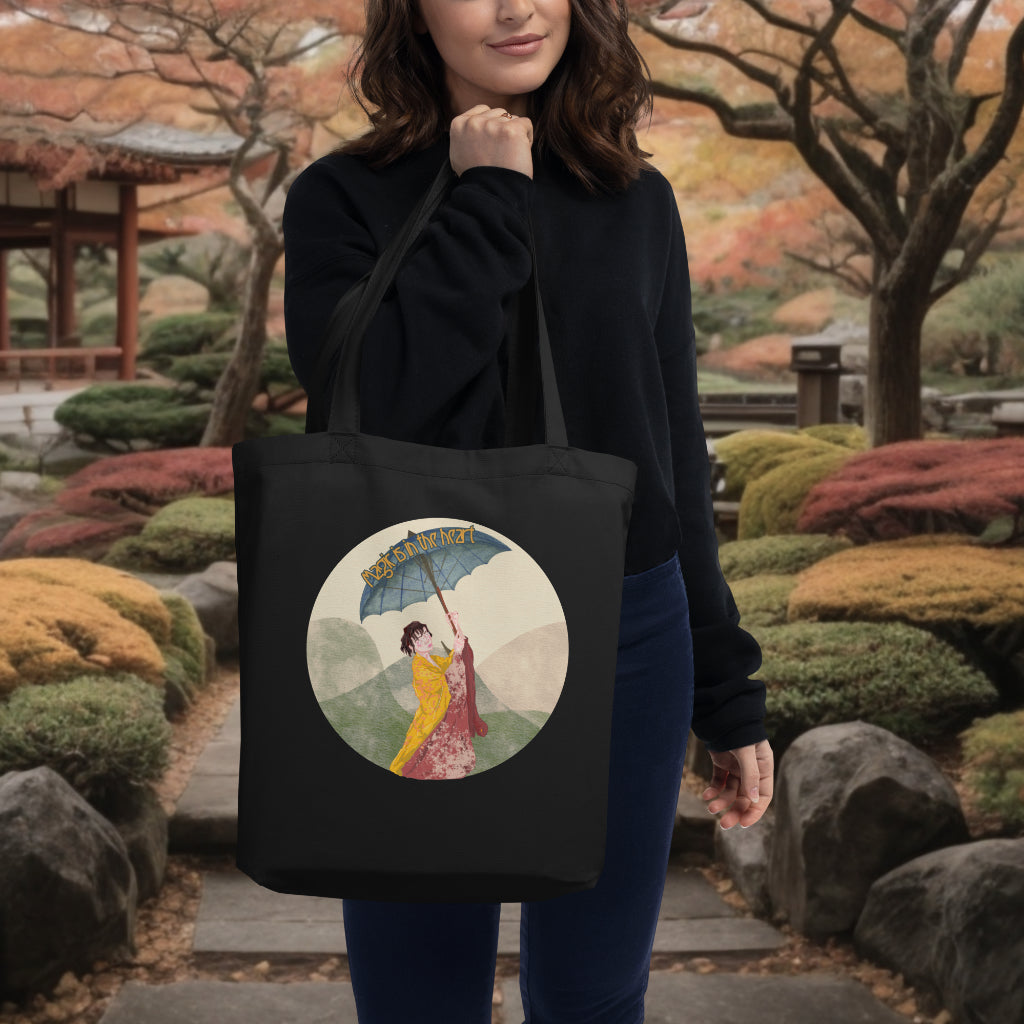 The 'Magic is in the Heart' black tote over a model's shoulder, featuring the vibrant scene of the woman in the kimono, merging practicality with a touch of enchantment and cultural appreciation.