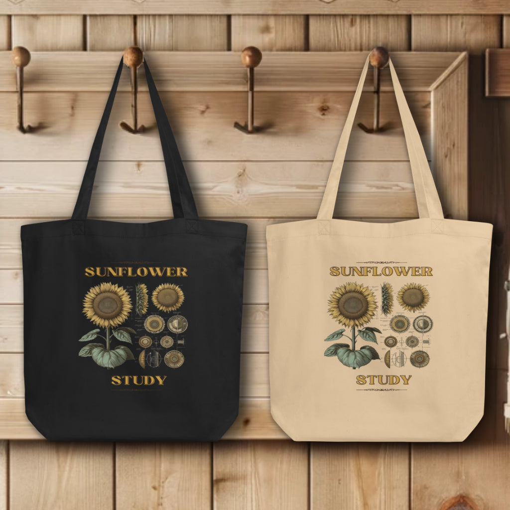 Group display of 'Sunflower Study' Sunflower Tote Bags in black and oyster, hanging on wall hooks, each bag featuring a detailed botanical illustration of a sunflower, showcasing the fusion of scientific art and sustainable fashion.