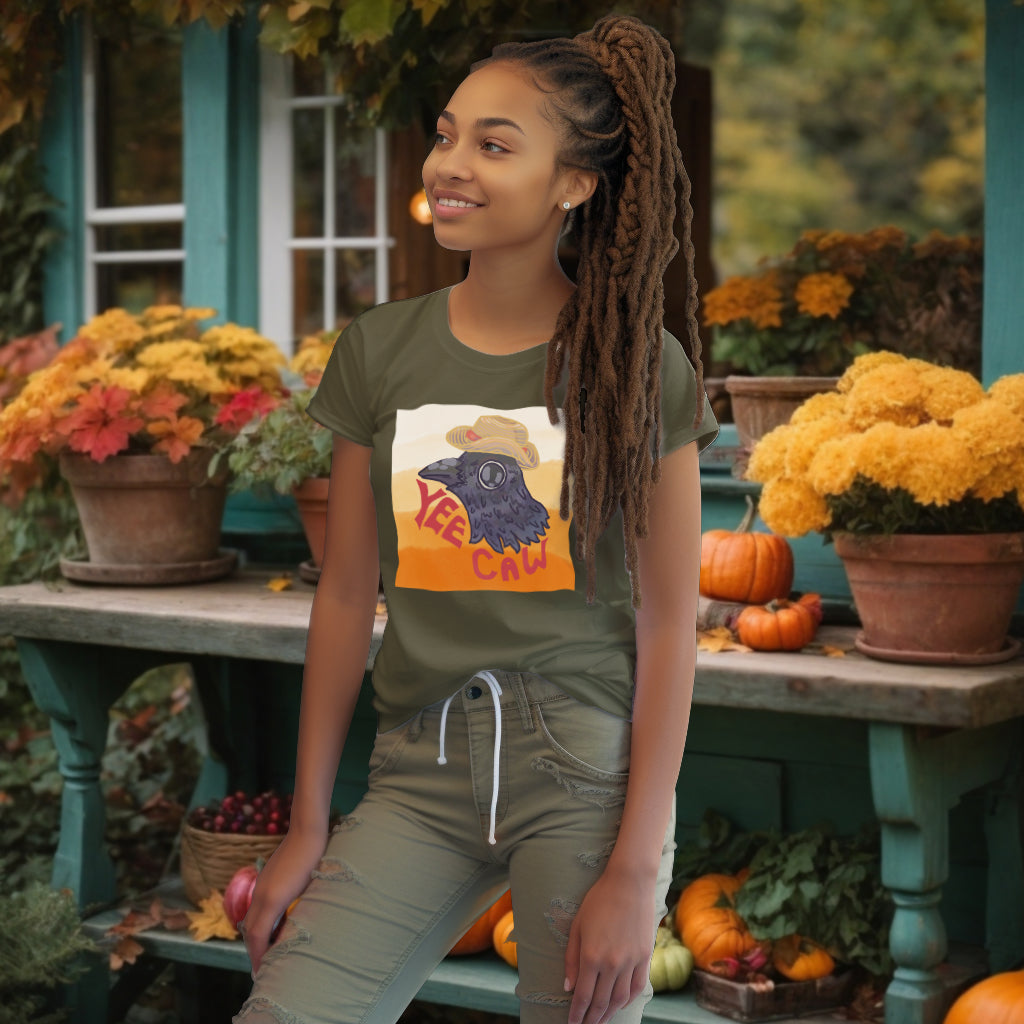 Showcasing the 'Yee Caw' Khaki T-Shirt, the model highlights the joyful watercolor crow and straw hat, a celebration of humor and adventure in everyday style.