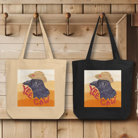 Collection of 'Yee Caw' Totes in black and oyster colors, elegantly displayed on hooks, each tote illustrating the mischievous crow head design, embodying the spirit of individuality and whimsy.
