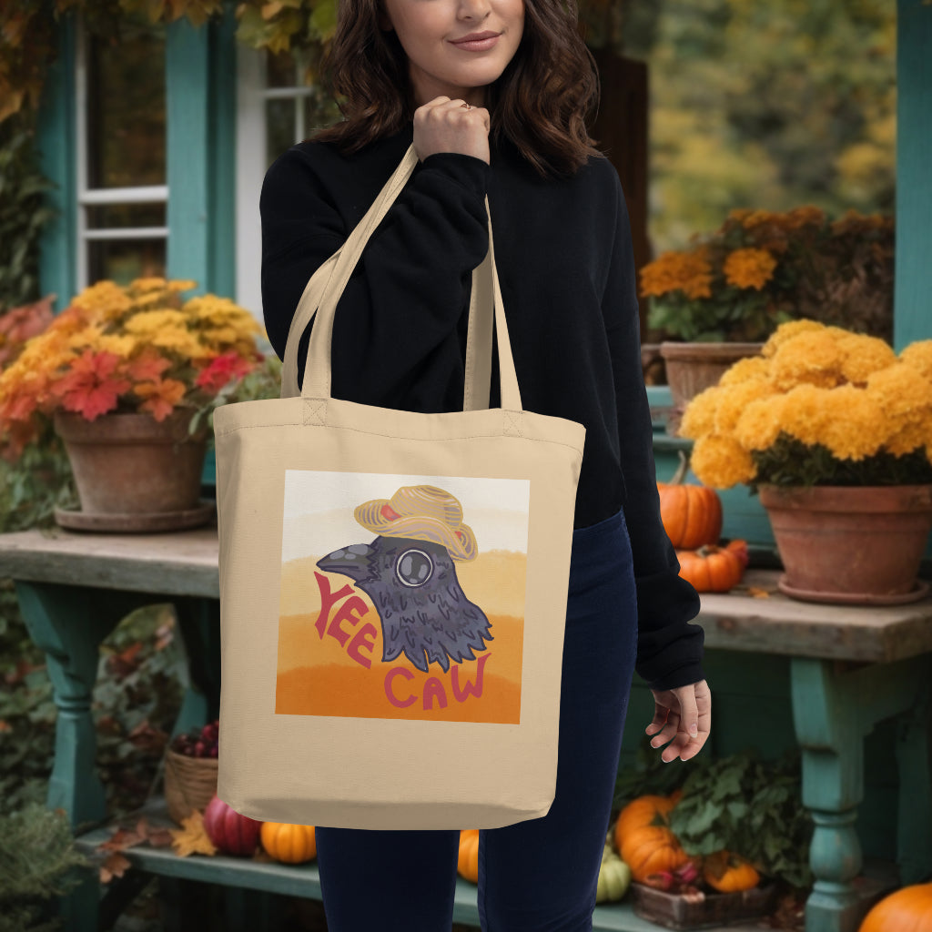 The 'Yee Caw' Tote in oyster color carried by a model, highlighting the spirited crow in its straw hat, ideal for eco-conscious individuals who love to express their joyous side.