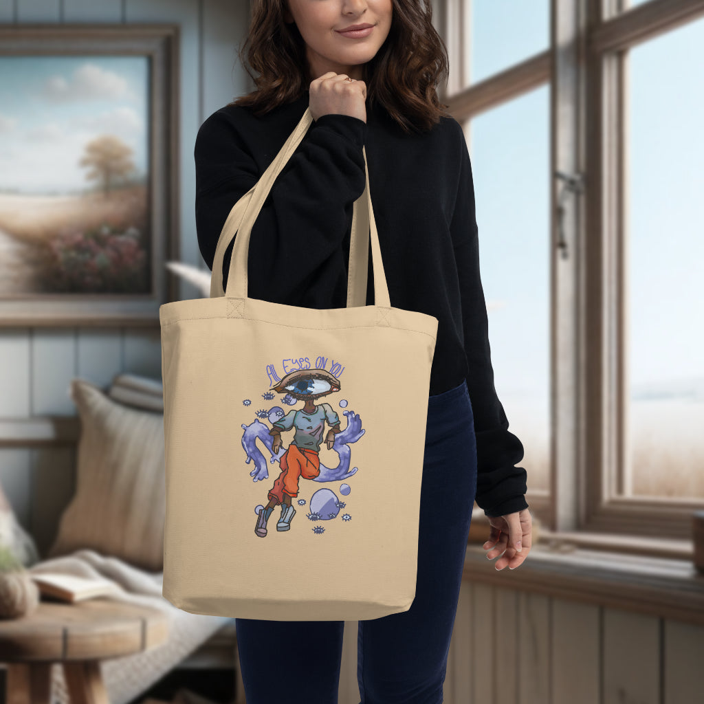 The 'All Eyes On You' Tote in oyster carried by a model, bringing to life the artistic watercolor depiction of an eye-shaped head, offering a blend of whimsy and functionality for the eco-conscious consumer.