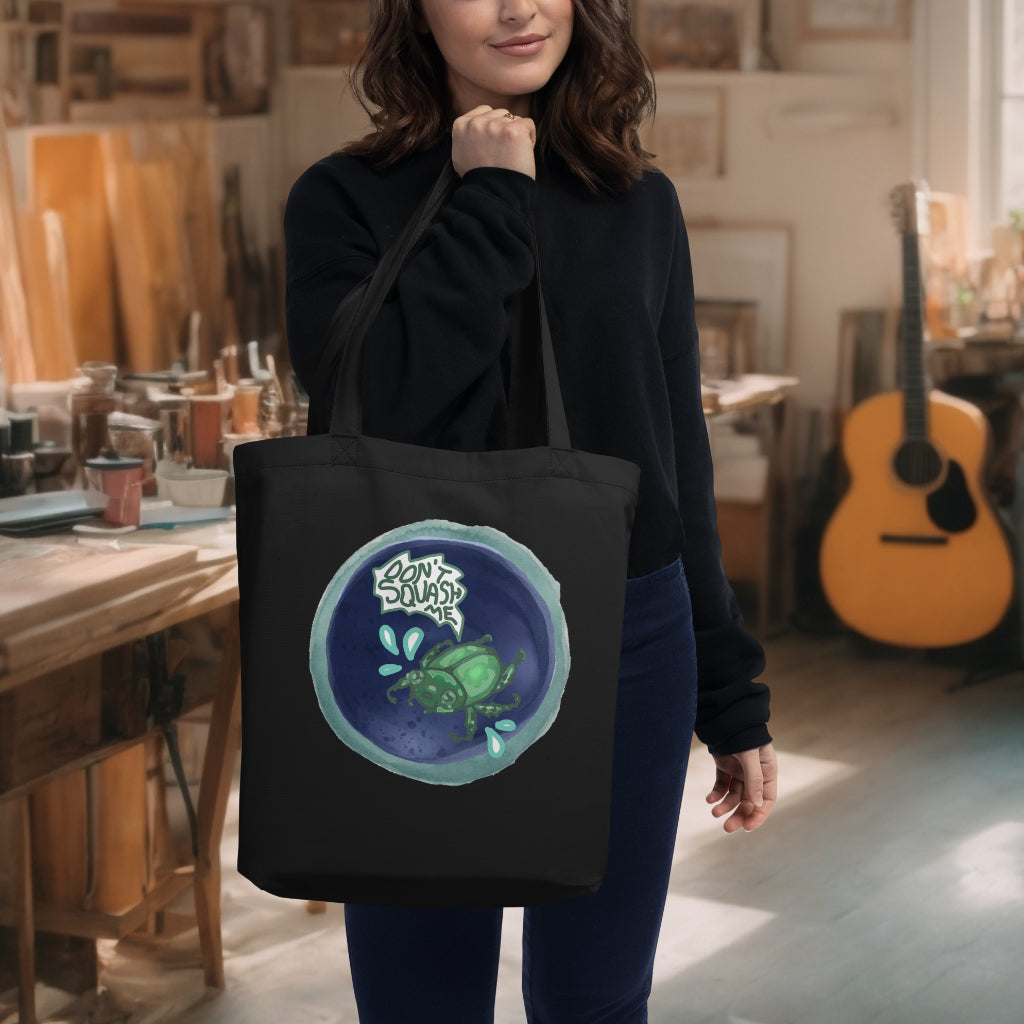 Model carrying the 'Don't Squash Me' Tote in black, showcasing the charming watercolor scared beetle, a lighthearted yet meaningful design for the environmentally conscious individual.