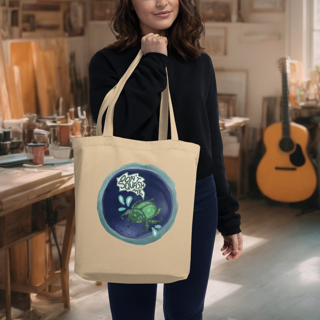 The 'Don't Squash Me' Tote in oyster color carried by a model, highlighting the unique beetle design, ideal for those who appreciate artful expression and environmental mindfulness.