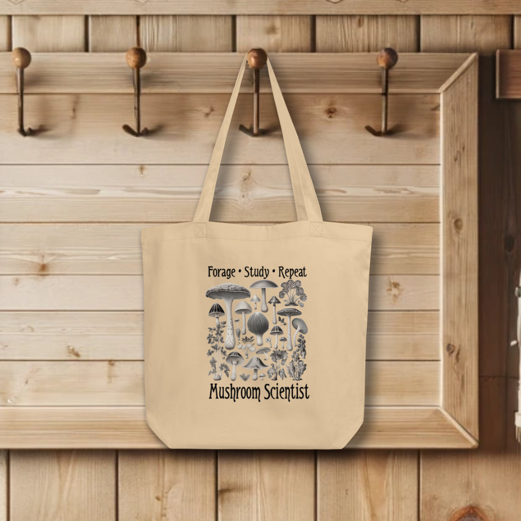 'Forage, Study, Repeat' Tote Bag in oyster color, displaying realistic, hyper-detailed mushroom renderings, capturing the essence of a scholar's dedication to fungi study.