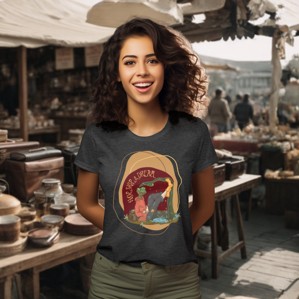 The 'Hop, Skip, Dream' organic cotton tee in Dark Heather Grey, worn by a model to display the whimsical frog-human artwork, inspiring a playful embrace of adventures and dreams.