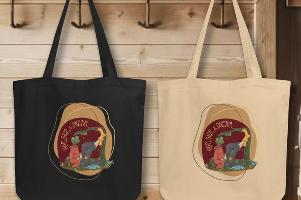 Group of 'Hop, Skip Dream' Totes in black and oyster, elegantly displayed on hooks, each tote adorned with the imaginative watercolor design, embodying the spirit of adventure and creativity.