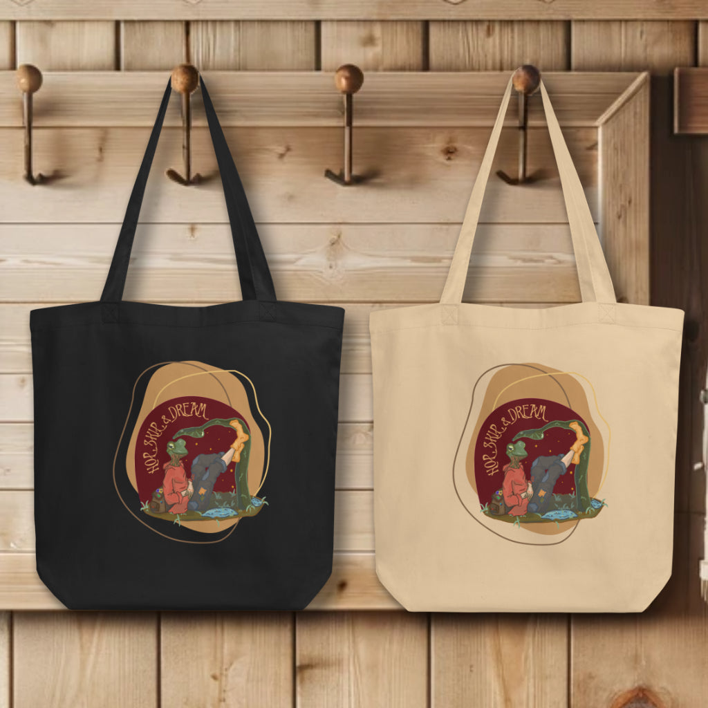 Group of 'Hop, Skip Dream' Totes in black and oyster, elegantly displayed on hooks, each tote adorned with the imaginative watercolor design, embodying the spirit of adventure and creativity.