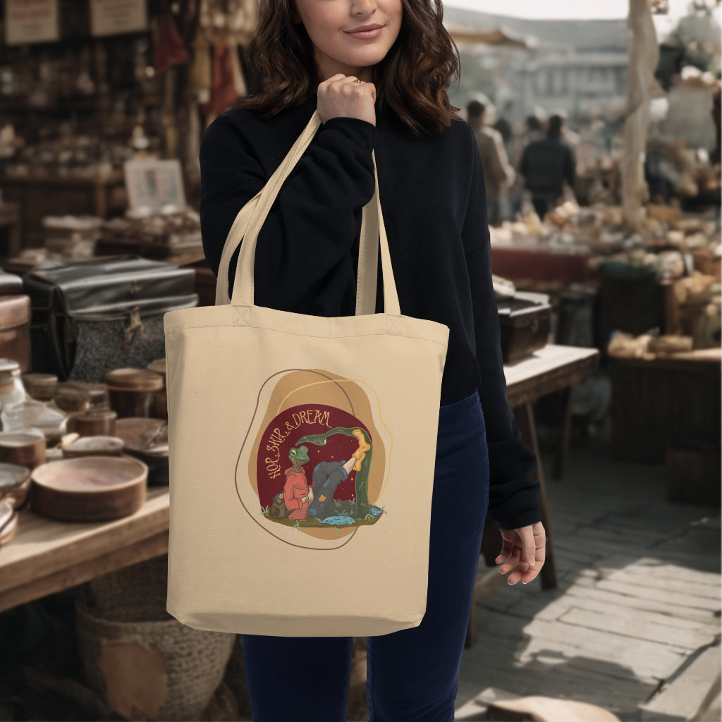 The 'Hop, Skip Dream' Tote in oyster color carried by a model, highlighting the artistic and vibrant frog-human figure, ideal for eco-conscious individuals who cherish creativity and individuality.