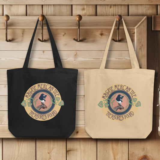 Group display of 'Magpie Mercantile Logo' Totes in black and oyster, hanging on wall hooks, each featuring the elegant watercolor magpie logo, symbolizing the brand's commitment to curating unique and precious finds.