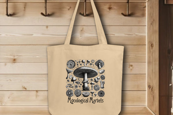 'Mycological Marvels' Tote Bag in oyster, hanging on wall hooks, showcasing a detailed botanical illustration of various mushrooms, celebrating the diversity and intricacy of fungi in a sustainable format.