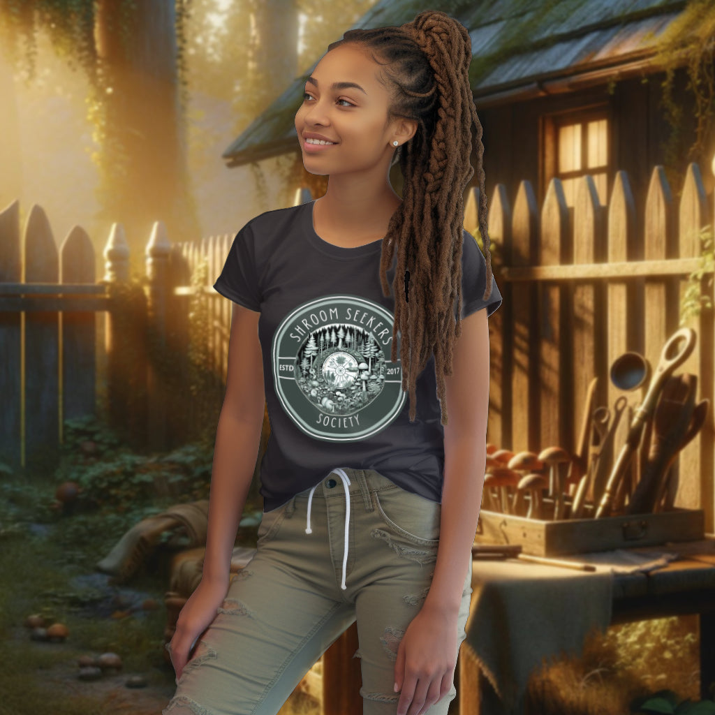 Featuring 'Shroom Seekers Society' Tee Shirt in anthracite, the model displays an artistic rendition of mushrooms and pines in a circular pattern, celebrating the interconnectedness of forest life.