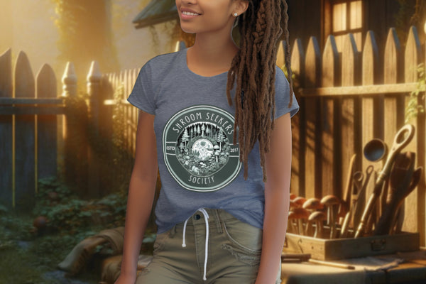 Model wearing 'Shroom Seekers Society' Tee Shirt in dark heather blue, depicting a forest ecosystem with mushrooms and pine trees, symbolizing the unity and fascination with the natural world.