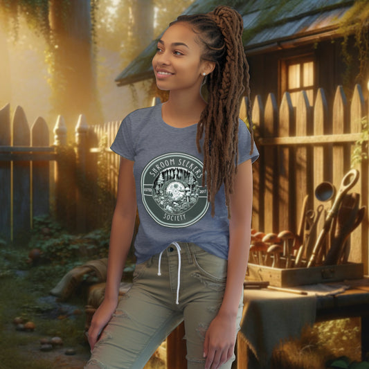 Model wearing 'Shroom Seekers Society' Tee Shirt in dark heather blue, depicting a forest ecosystem with mushrooms and pine trees, symbolizing the unity and fascination with the natural world.