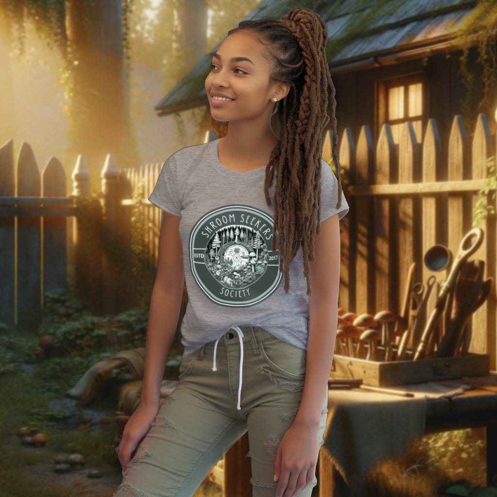 Wearing 'Shroom Seekers Society' Tee Shirt in heather grey, the model presents a piece that combines style and ecological awareness, perfect for explorers of nature’s fungal treasures.