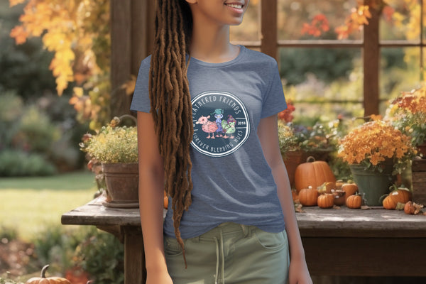 Model wearing the 'Feathered Friends' T-Shirt in Dark Heather Blue, adorned with a watercolor design of three ducklings with playful accessories, celebrating the joy of diverse friendships.