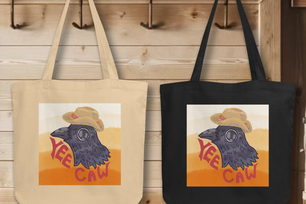 Collection of 'Yee Caw' Totes in black and oyster colors, elegantly displayed on hooks, each tote illustrating the mischievous crow head design, embodying the spirit of individuality and whimsy.