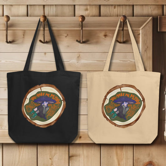 Array of 'You Make Me Mushy' Totes showcased in black and oyster variants, each adorned with the whimsical scene set against a log end round, a celebration of nature's wonder and the power of friendship.