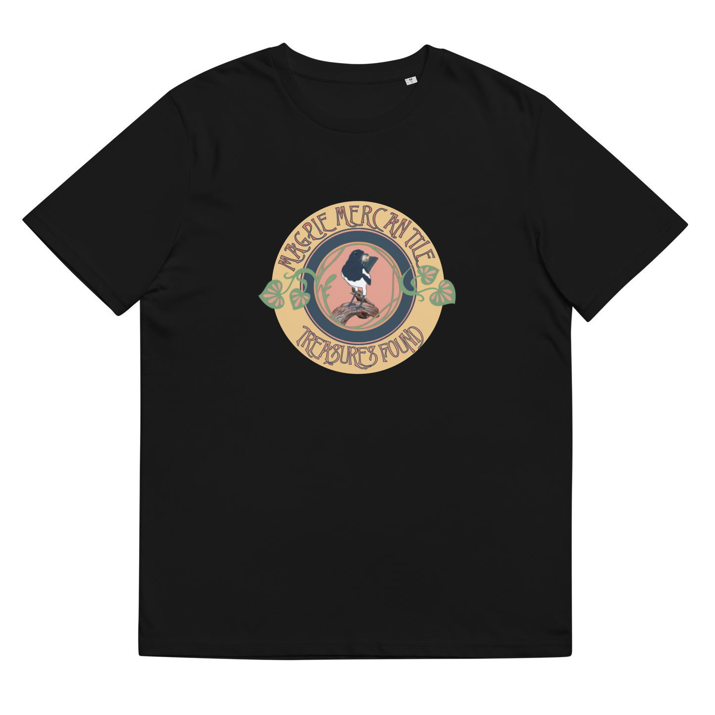 Lay-flat image of the 'Magpie Mercantile Logo' T-Shirt in Black, highlighting the detailed watercolor magpie holding a gold ring, set within an Art Nouveau inspired botanical motif, a representation of unique finds and elegance.